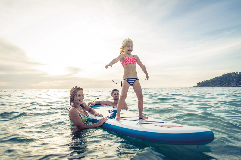 Family teaching a young daughter how to surf