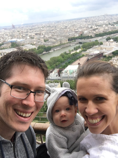 A father, baby and mother pose in front of the central Paris cityscape