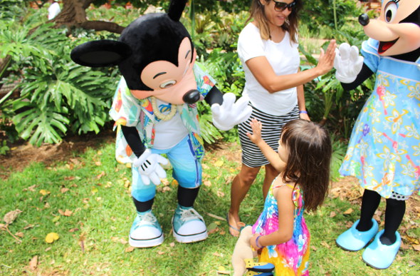 A mother and daughter give high fives to Mickey and Minnie characters