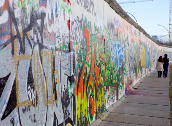  couple walk along berlin wall at east side gallery