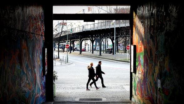  couple walking on berlin street looking from graffiti alley