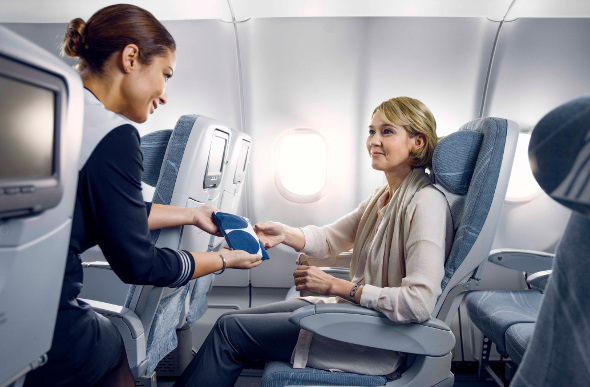 A Finnair flight attendant hands a passenger a Marimekko print amenity kit