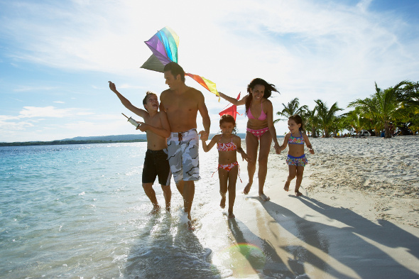 Family running on beach at sunset