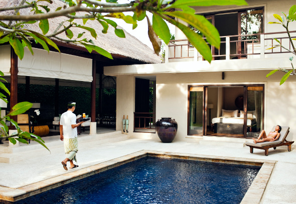 Pool butler brings drink to woman lounging by pool.