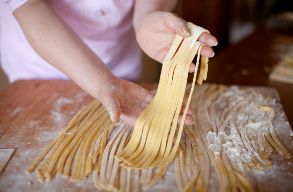 A woman holds some fresh pasta in her hands