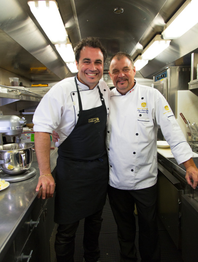 TV chef Miguel Maestre and Rocky Mountaineer Executive Chef Jean Pierre Guerin stand in the onboard kitchen of the Rocky Mountaineer train