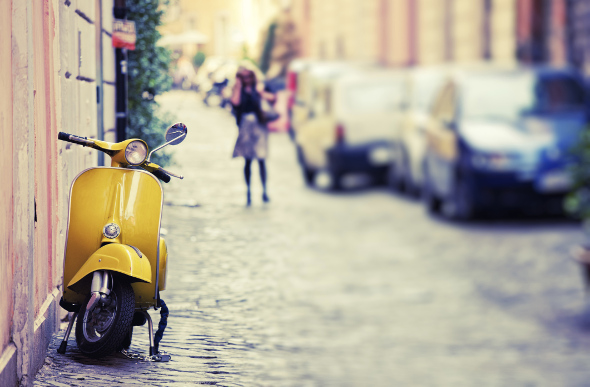 A vintage yellow Vespa is parked on a charming street in Rome