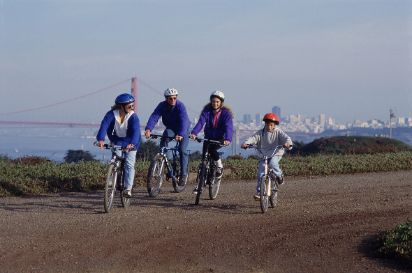 family riding bikes with golden gate bridge and san francisco in background