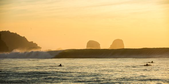 surfers paddling out at pichilemu chile at dusk