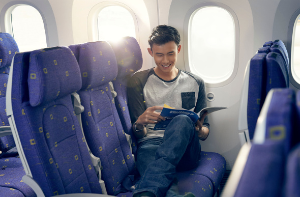 A passenger stretches his legs across the airline seats on a Scoot plane