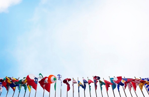  Row of international flags against a blue sky.