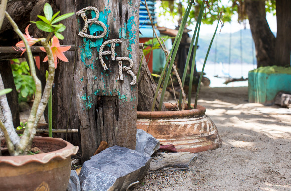 A bar sign pointing to a beachfront bar on a Thailand beach