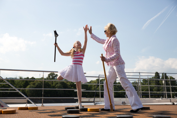 Mother playing shuffle board with her daughter on the deck of a cruise ship