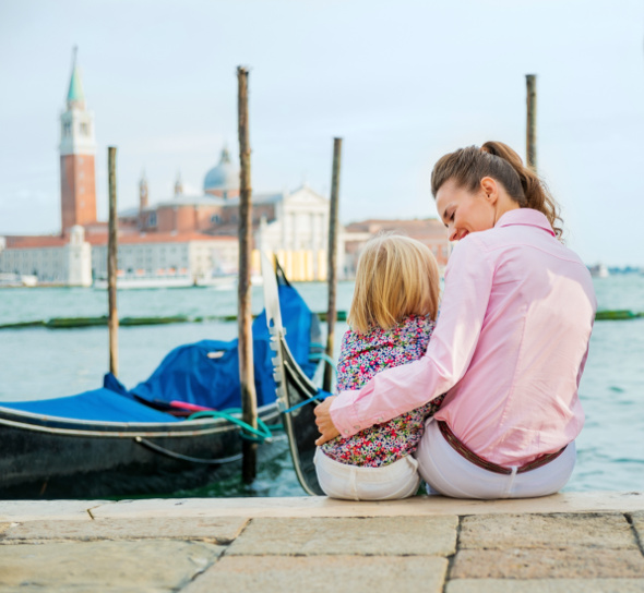 Mother hugging daughter at waters edge in venice