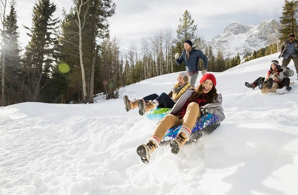 Friends sliding down a snowy mountain in blow up tubes.