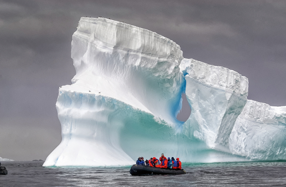 Massive iceberg and zodiac with people