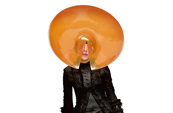 Stylist Isabella Blow wears an orange acrylic disk hat.