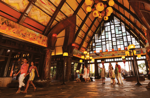 A family being greeted inside the Hawaiian-style lobby of Aulani, A Disney Resort & Spa