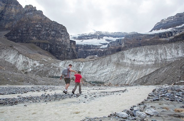 A father and son hiking next to a small rocky river in Banff.