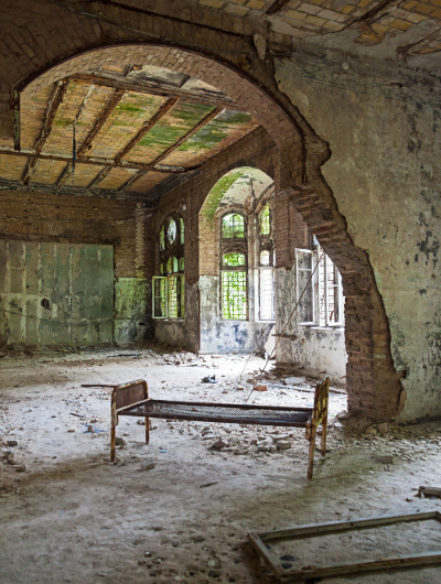 Ruined room with rusted bed in abandoned hospital