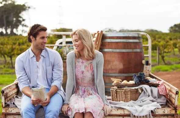  A couple sitting on the back of a trailer with a picnic basket and map. 