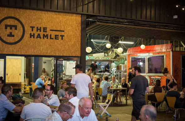 People sitting and eating around food trucks