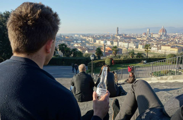 Traveller sitting on steps with beer overlooking Budapest