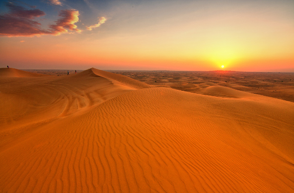 The sun sets over the desert dunes outside Dubai.