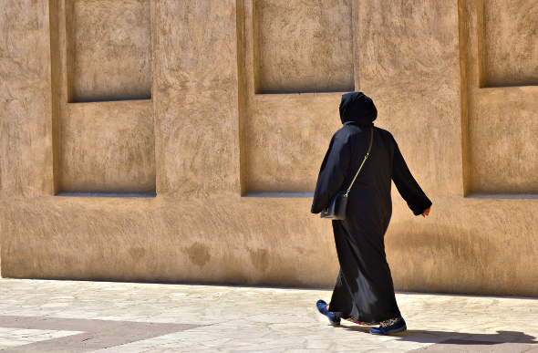 Woman dressed in traditional garb walking past Al-Fahidi in Dubai