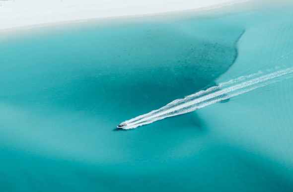 A lone boat leaves a white wake in the blue waters of the Whitsundays.