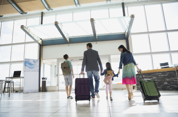 A family walking through an airport with luggage in tow