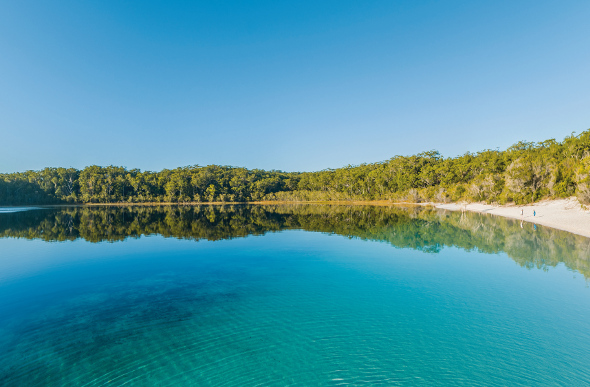 The clear blue waters of Lake McKenzie reflect the sky, as its white-sand beach retreats into the bush on Fraser Island.