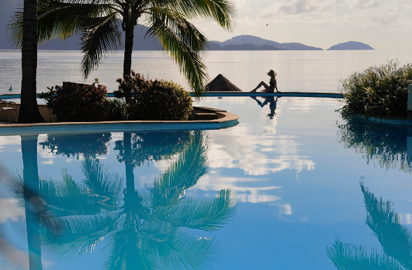 Woman relaxing at pool over looking ocean