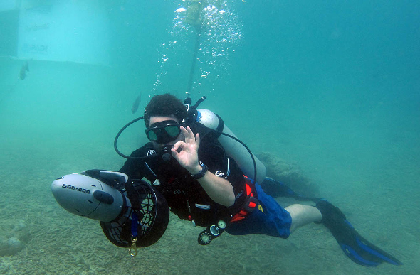 A diver under water with a Seadoo electric dive scooter