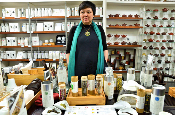 Vivian Mak standing in her tea house with leaves and pots behind her