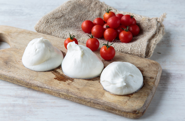 Beautifully presented burrata on wooden board with cherry tomatoes