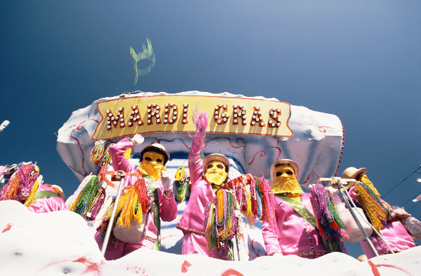 Masked men and women throw beads from a Mardi Gras float in New Orleans, USA.