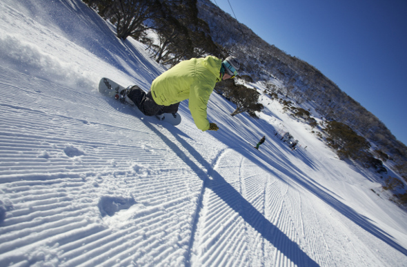 A snowboarding riding down a slop at Perisher