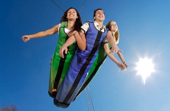 Three people attached together in the swoop full body sling bungee.