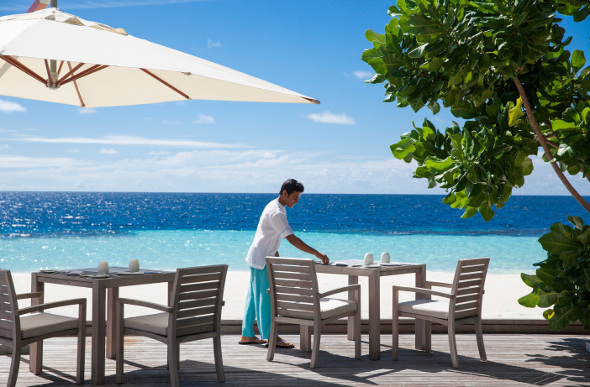 A waiter lays a table at the outdoors Blue Salt restaurant at Outrigger Konotta Maldives Resort