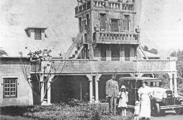 A black and white photo of the Paronella family standing in front of the castle. Jose with daughter Teresa, son Joe with Jose's wife Margarita