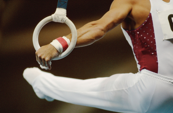 A close-up of a male gymnast on the rings.