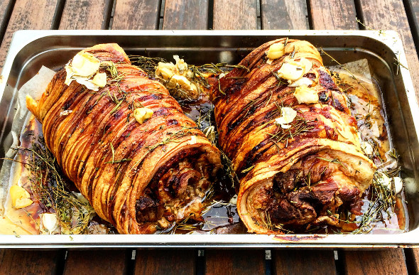 Two roasted porchettas in a baking tray