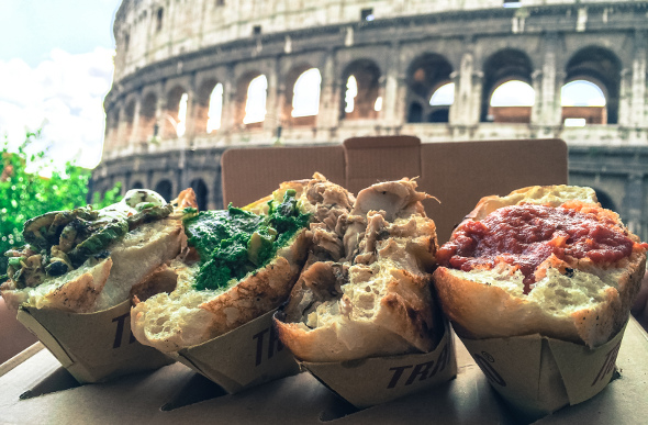 Three trapizzino lined up with the Colosseum in the background