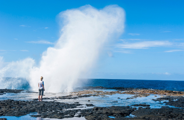 A tourist watches a sky-high jet of water at the Alofaaga Blowholes in Samoa.