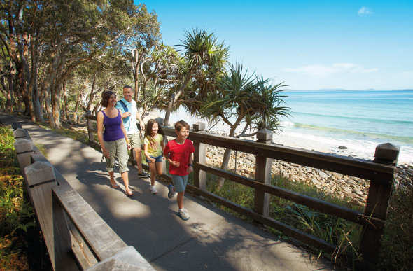 A family take a walk along the coastal path at Noosa.