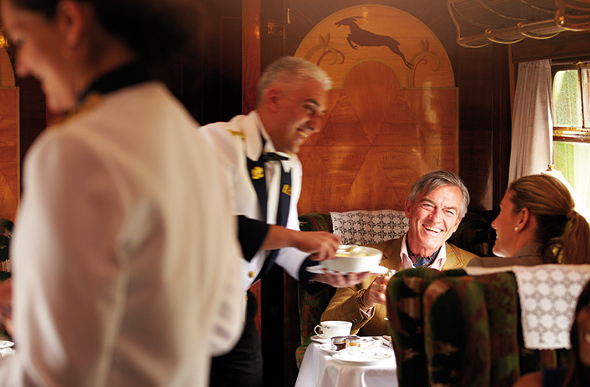 Two train passengers being served by a waiter