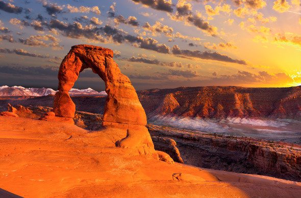 The Delicate Arch rock formation glows orange as the sun sets in Utah's Arches National Park.