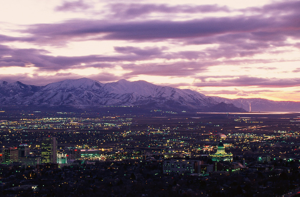 Salt Lake City twinkles at twilight, with snow-capped peaks in the background.