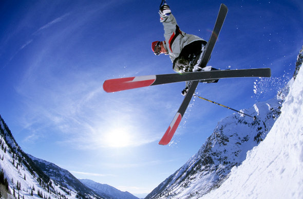 A skier gets airborne against the bright blue sky at Utah's Snowbird ski resort.